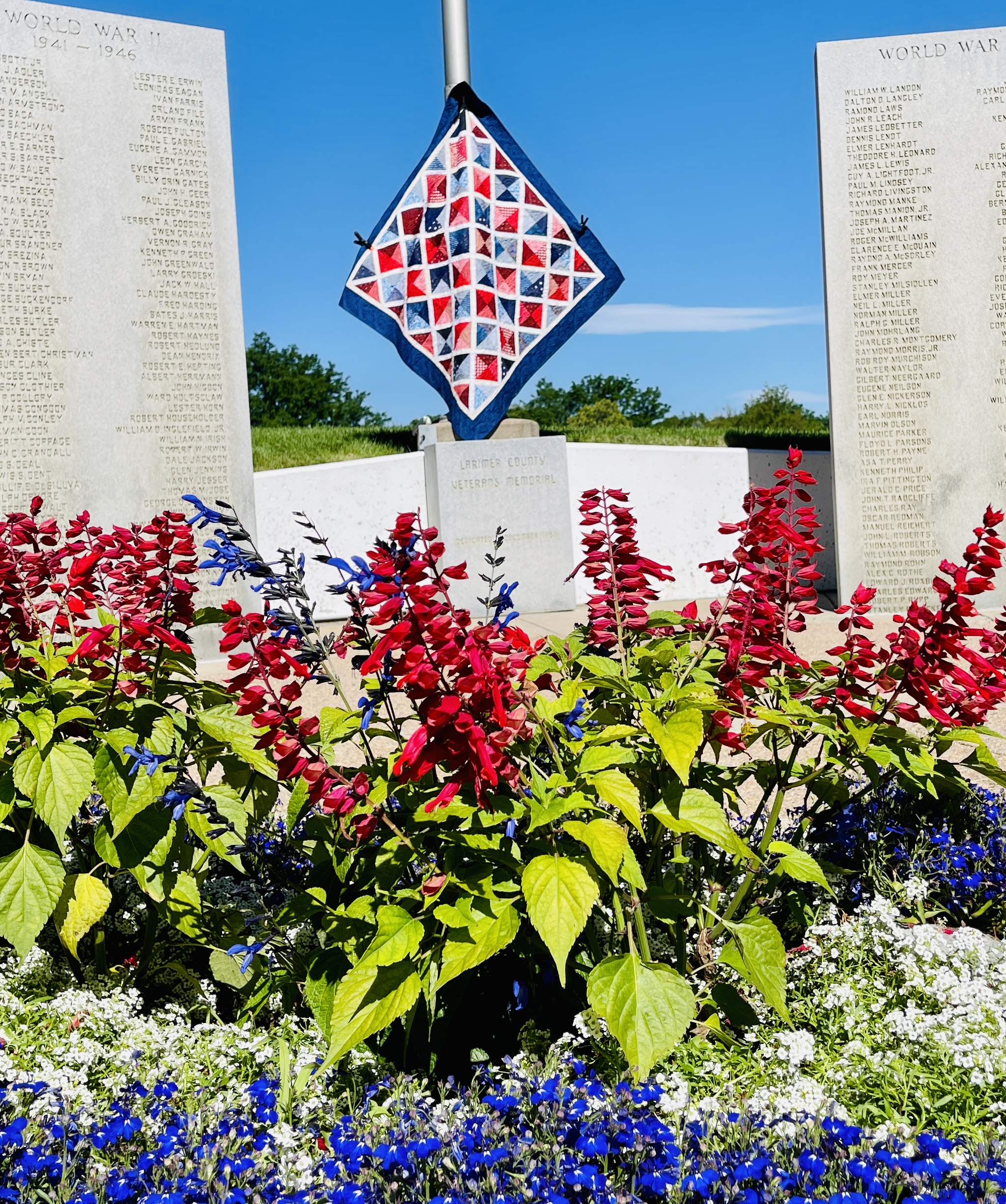 Patriotic quilt hanging between World War 2 monuments